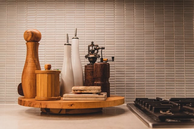 collection of oils and spices on a wooden board next to a cooker